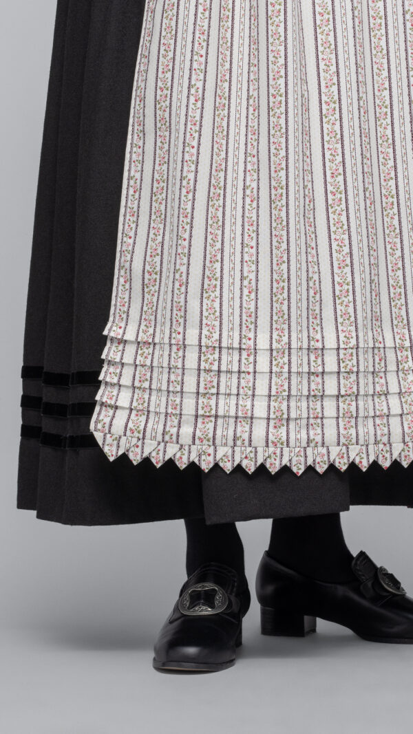 <span style="font-size: 19.2px; line-height: 27.648px;">Man kan bruke flere typer forkle til Fanabunaden. Kulørt forkle var mye brukt store deler av 1800-tallet og i høyeste høytid brukte man det hvite forkleet med heklekanter. Kulørt forkle er et bomullsforkle med blomstertrykk. Bunnen er lys og mønsteret kan variere. </span>