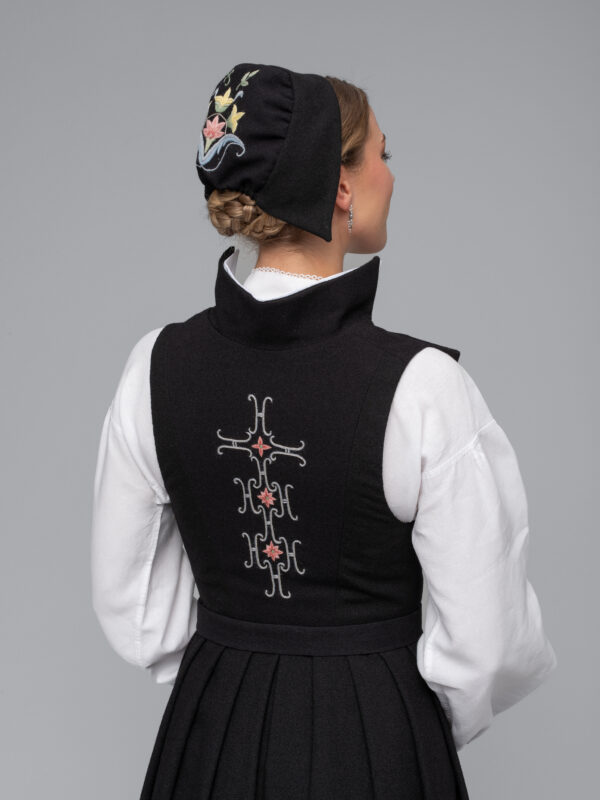 <p>Ryggen har rette linjer med brodert ornament sammensatt av 10 H-er